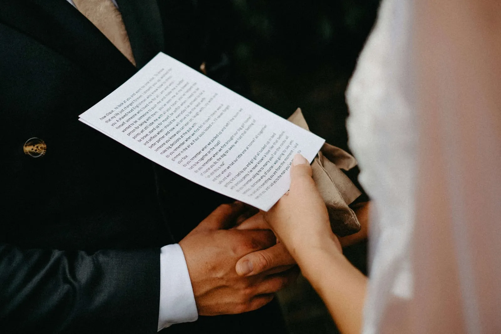 Ženích drží text sľubu a nevesta ho drží za ruku počas svadobného obradu